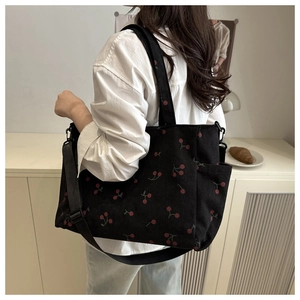 Détail du cabas en velours côtelé à motif cerises avec sangle et poche latérale