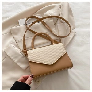 Detailed shot of beige woven texture and brown leather patchwork on a small square bag