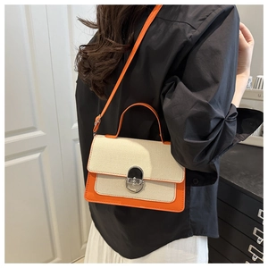 Detail of a contrast color crossbody bag with orange leather trim and silver metal lock