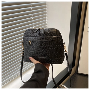 Detail of black embossed shell bag with gold hardware and woven texture strap