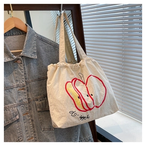 Detail view of white canvas tote bag with artistic apple print and casual cotton texture