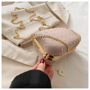 Macro detail of pink textured fabric evening bag with sparkling rhinestone buckle and chain