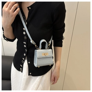 Detail of light blue croc-embossed mini square bag with metallic lock shown on model