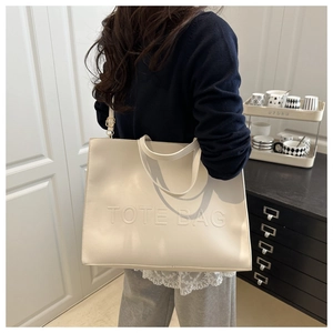 Macro detail of embossed TOTE BAG text on high-quality cream white leather tote bag