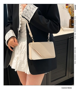 Détail du sac beige avec rabat texturé et barre décorative en métal doré clair