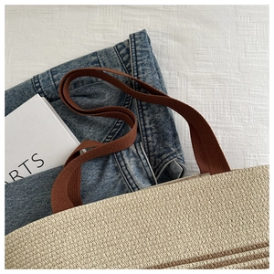 Detail of woven tote bag with beige and brown stripes and durable canvas shoulder strap