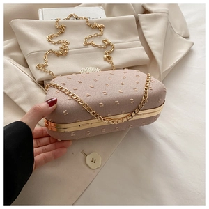 Detail of light pink pleated clutch with gold chain strap and rhinestone clasp