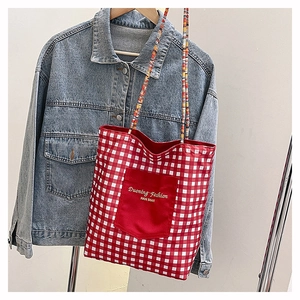 Close-up of red and white checkered tote bag featuring red patch pocket and beaded handles
