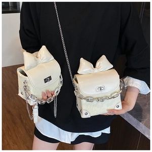 Detail view of mini cream bow crossbody bag with silver twist lock and chain strap