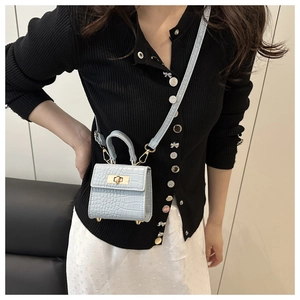 Detail of light blue crocodile embossed mini crossbody bag with metal twist lock on model