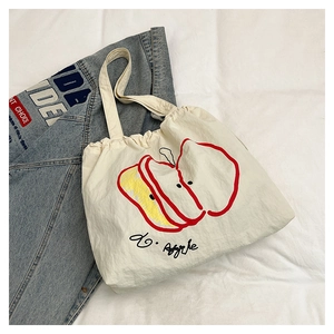 Detailed top view of a cream nylon tote bag featuring a cute red apple print design