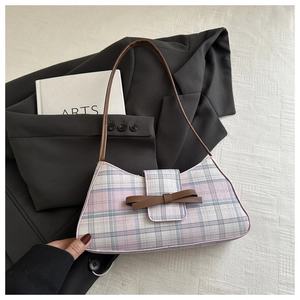 Detail of pink and blue checkered underarm bag with a brown leather bow on a blazer