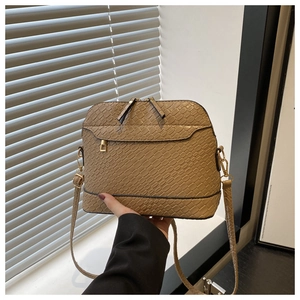 Close-up of khaki shell crossbody bag with textured snake pattern and gold metal zipper