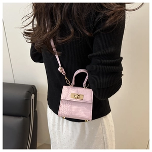 Detail view of pink crocodile pattern mini bag worn by model showing its actual size and scale