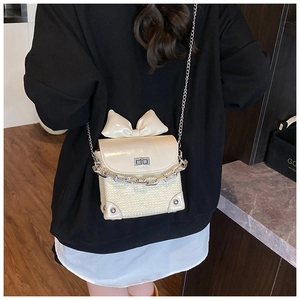 Detail of cream mini chain bag with large bow and woven texture on model