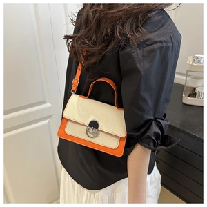 Detail of beige canvas and orange leather patchwork bag with silver metal lock closure
