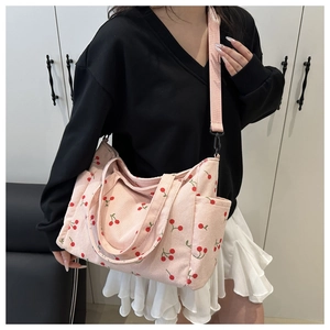 Détail du sac cabas en velours côtelé rose avec imprimé cerises, doubles poignées et bandoulière