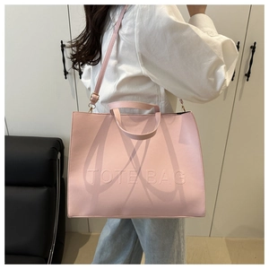 Pink tote bag detail with embossed lettering and adjustable shoulder strap for women
