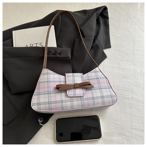 Detail of pink plaid underarm bag with brown leather bow accent and thin shoulder strap