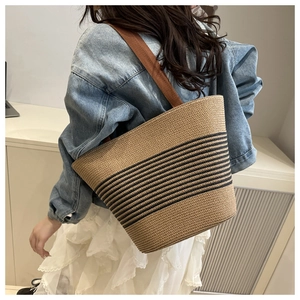 Detail of the woven straw tote bag texture and striped design on a casual summer outfit