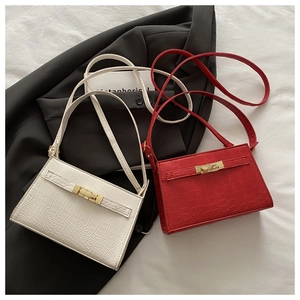 Detail of red and white faux crocodile texture handbags with golden turn-lock fasteners