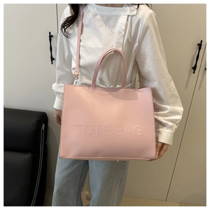 Detail of pink tote bag with embossed letters and adjustable crossbody shoulder strap