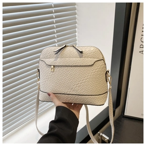 Detail of cream crocodile embossed crossbody bag with gold hardware and dual zippers