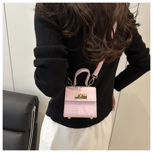Detail of pink croc-embossed mini square bag featuring gold lock and cross-body strap