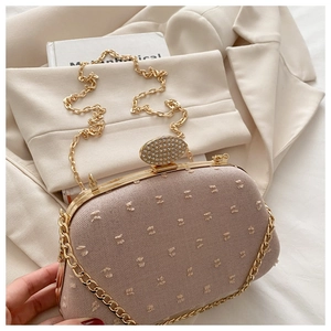 Close-up of diamond-encrusted lock and embroidered fabric on a luxury evening clutch bag