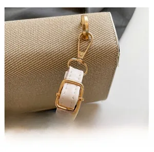 Détail de la bandoulière réglable en cuir crème avec boucles dorées sur le sac tissé