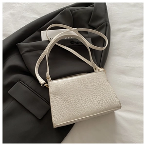 Detail of cream crocodile embossed texture on faux leather rectangular crossbody bag
