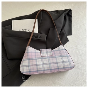 Detail of pink and blue plaid underarm bag with slim brown leather strap on blazer