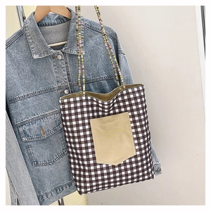 Detail of checkered canvas tote bag with embroidered pocket and colorful beaded strap