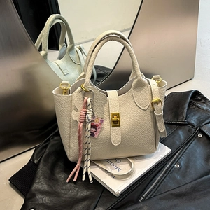 Minimalist cream white lychee grain bucket bag featuring gold hardware and a cute charm