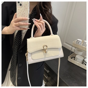 Detail of a creamy white contrast handbag featuring canvas texture and golden metal buckle