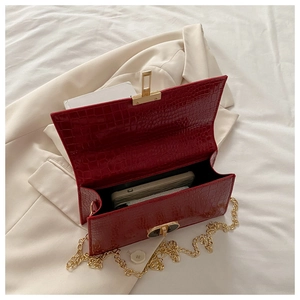 Detail of red croc-embossed shoulder bag showing interior space and gold chain strap