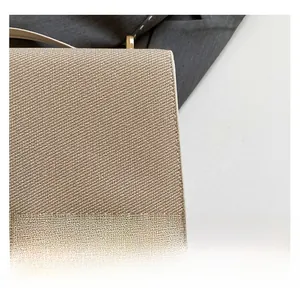 Gros plan détaillé du tissu tissé beige et de la boucle en métal doré sur le sac bandoulière