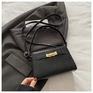 Detail of black crocodile texture PU leather handbag with elegant gold metal twist lock