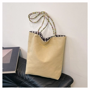 Detail view of canvas tote bag showing colorful braided handles and checkered lining
