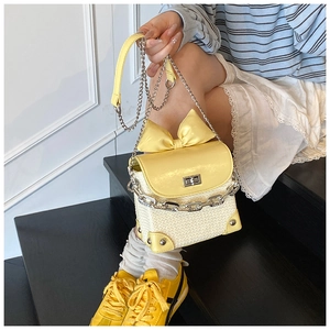 Detail of yellow bow shoulder bag with metal chain strap and woven texture finish