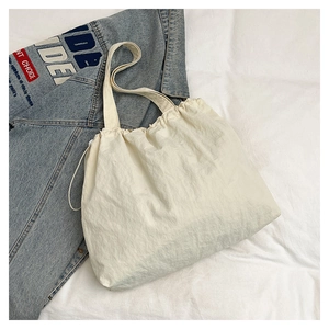 Detail of cream-white drawstring tote bag with crinkled texture and spacious interior