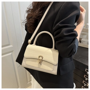 Detail of cream woven leather bag featuring a gold horseshoe buckle on a black blazer