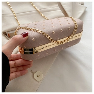 Detail of pink-purple hard-shell evening clutch with velvet texture and gold metal chain
