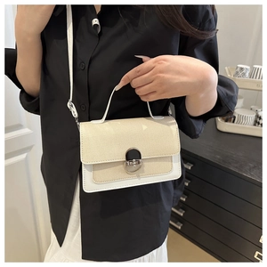 Detail of a beige woven and white leather square crossbody bag with silver twist lock