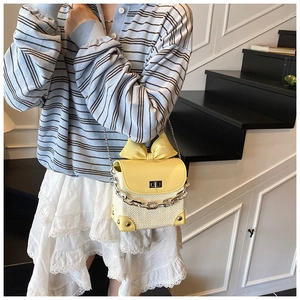Detail showing woven texture contrast crossbody bag with chic 3D bow and metal chain