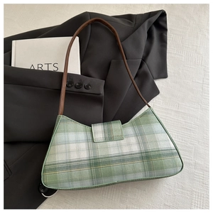 Detail of green plaid woven shoulder bag with brown leather strap and fold-over flap