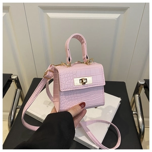 Detailed view of pink croc-embossed leather handbag with gold twist lock and handle