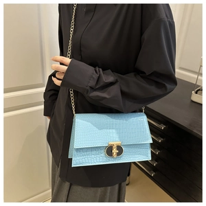 Detail of light blue crocodile embossed bag with gold chain strap and metal clasp