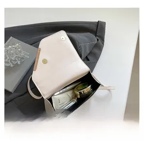 Vue détaillée d'un sac bandoulière beige montrant l'espace pour téléphone et maquillage