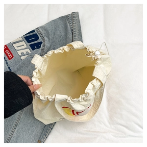 Detail view of white canvas tote bag with drawstring closure and interior compartment